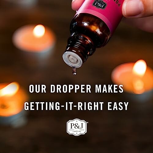 Essential oil dropper with lit candles in the background.